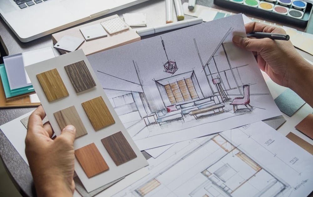 Hands holding timber finish samples over an interior sketch