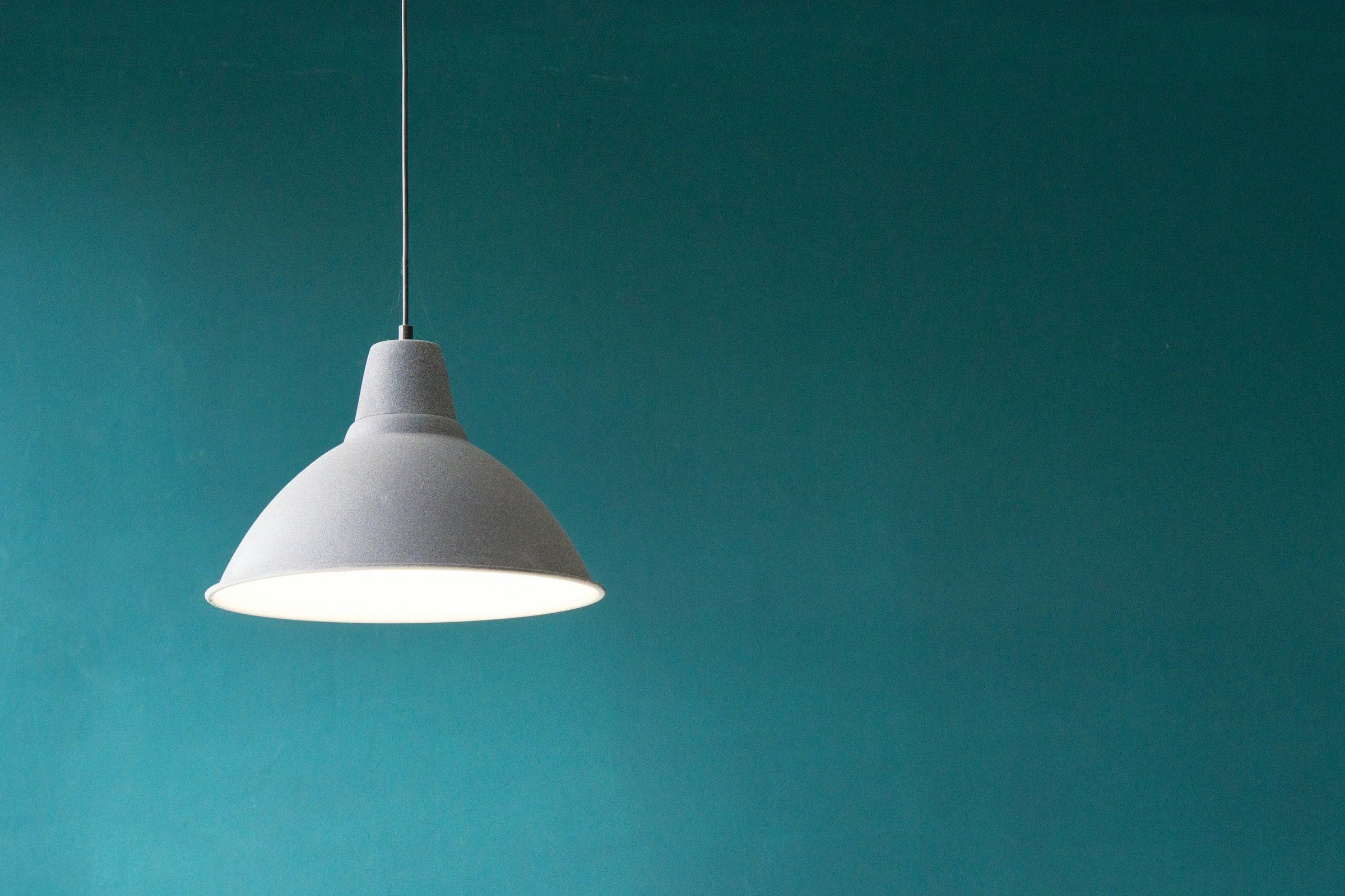 White pendant lamp against a deep teal wall